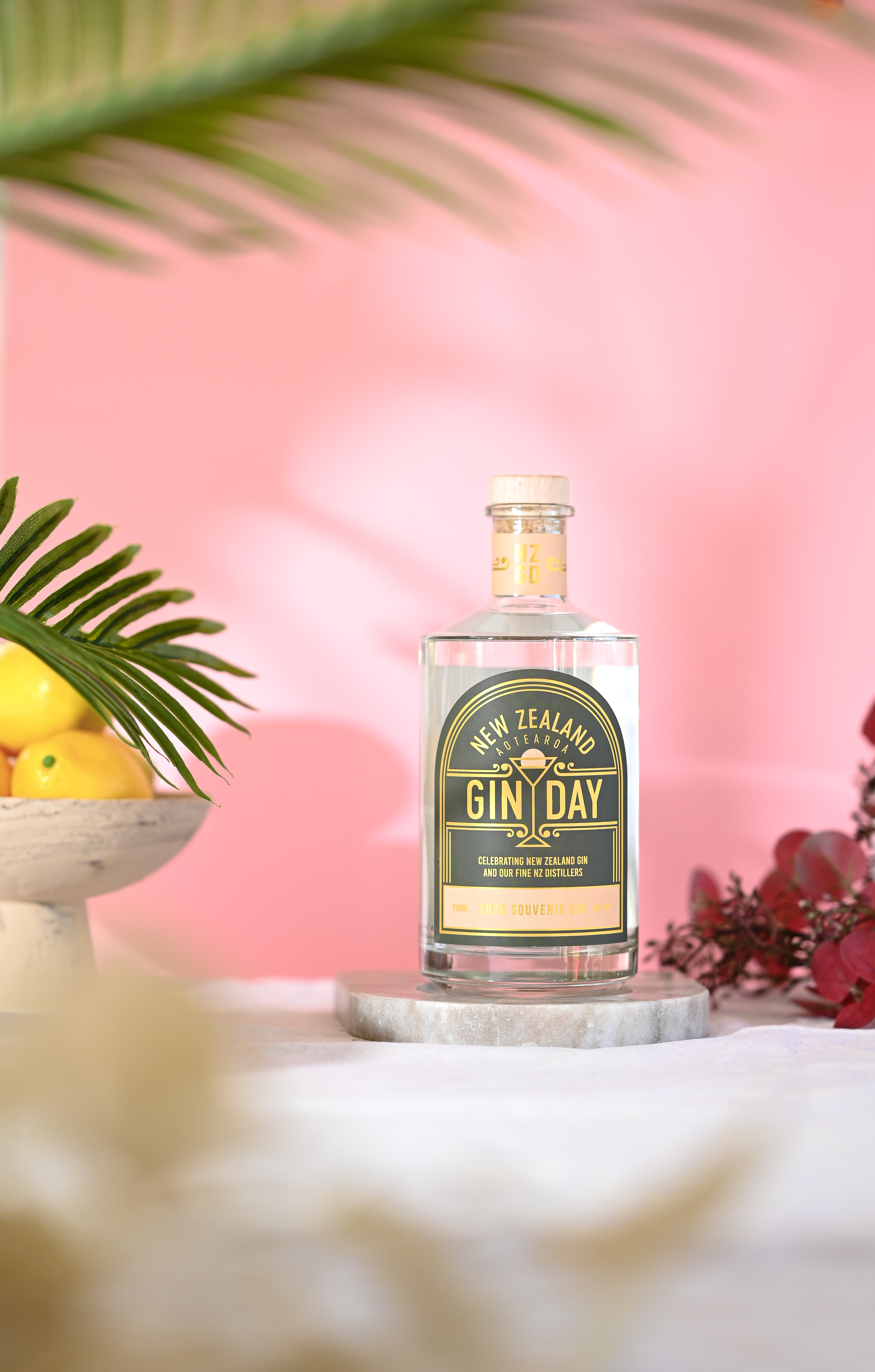 Bottle of NZ Gin Day Gin with a pink background and bowl of lemons