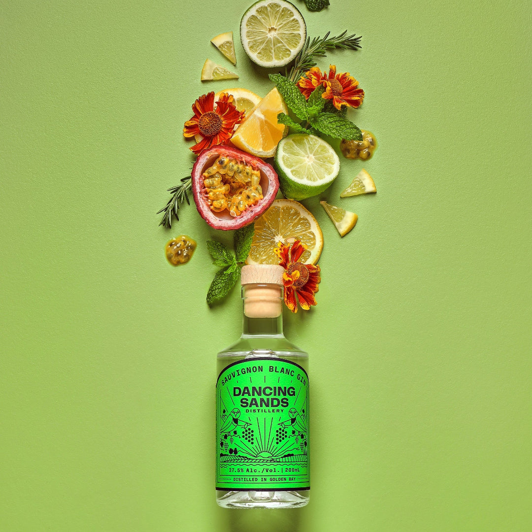 Bottle of Dancing Sands Sauvignon Blanc gin with garnishes on a green background